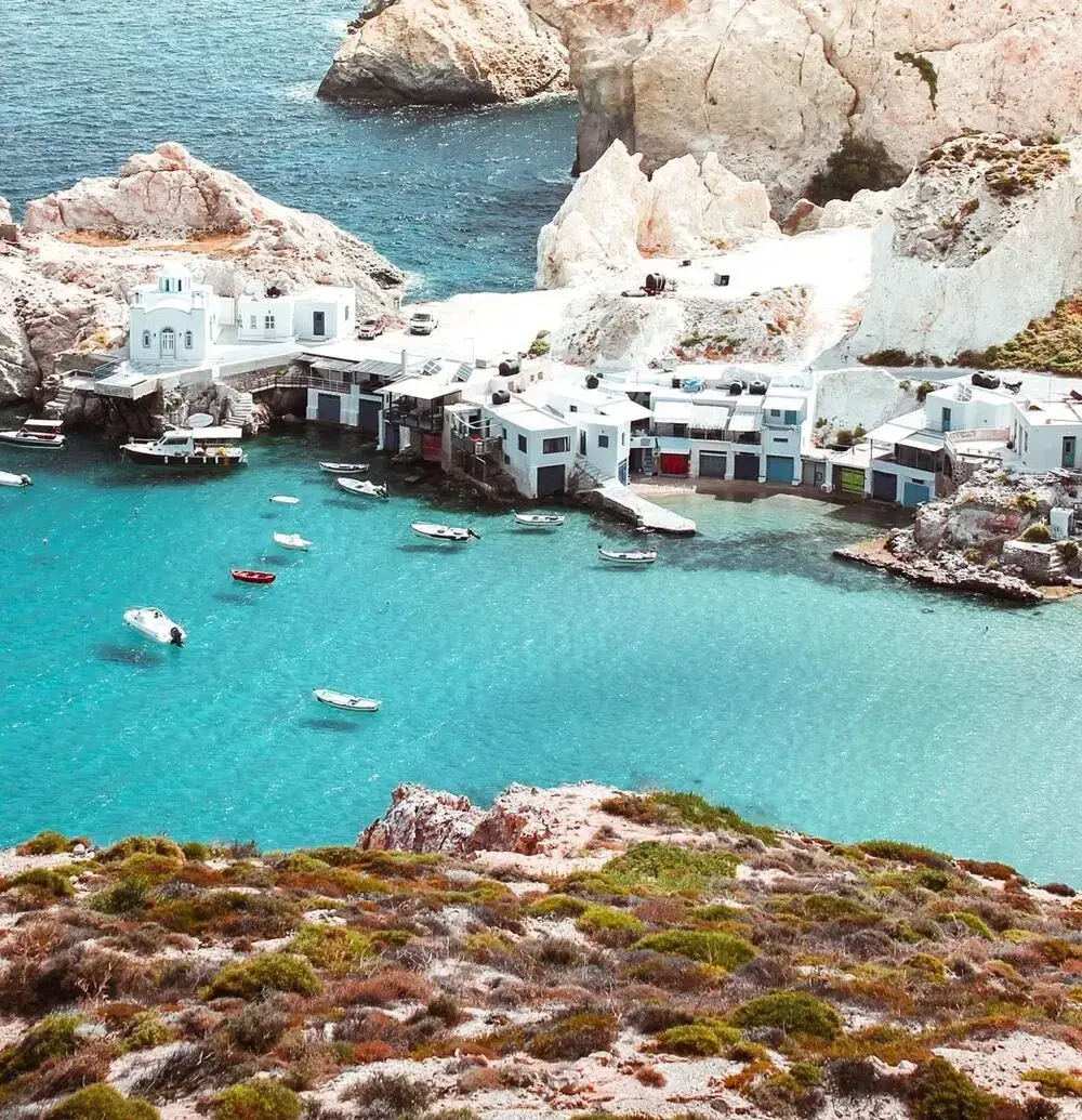Isla de Milos con acantilados blancos, bahía turquesa y pueblo cicládico en Grecia